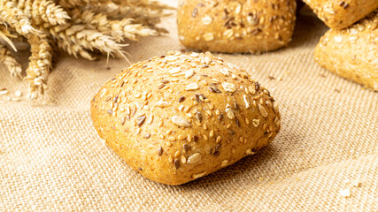 Rustic rye. Fresh loaf of rustic traditional bread with wheat grain ear or spike plant on linen texture background. Bakery with crusty loaves and crumbs. Design element for bakery product label.