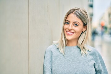 Young blonde girl smiling happy standing at the city.