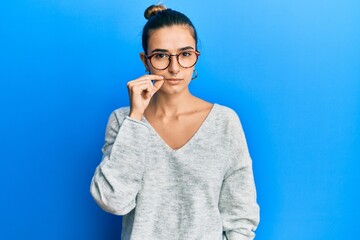 Young hispanic woman wearing casual clothes mouth and lips shut as zip with fingers. secret and...