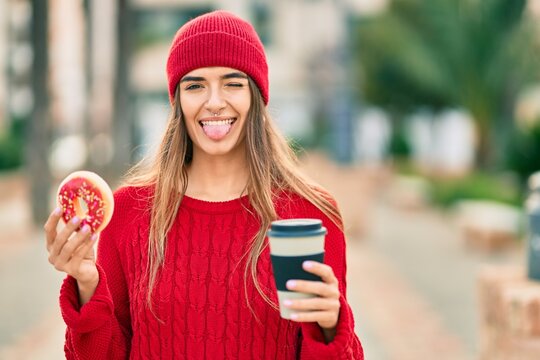 Young hispanic woman wearing wool cap having breakfast at the city.