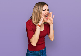 Young blonde girl wearing casual clothes shouting angry out loud with hands over mouth