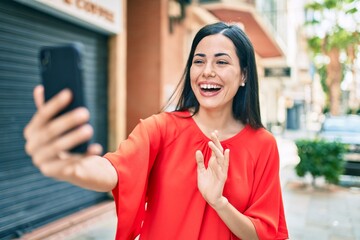 Young latin girl smiling happy doing video call using smartphone at the city.