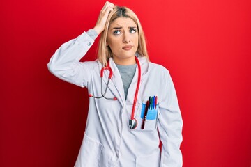 Young caucasian woman wearing doctor uniform and stethoscope confuse and wonder about question. uncertain with doubt, thinking with hand on head. pensive concept.