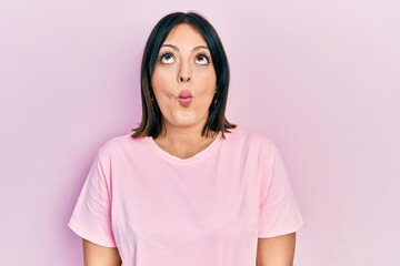 Fototapeta premium Young hispanic woman wearing casual pink t shirt making fish face with lips, crazy and comical gesture. funny expression.
