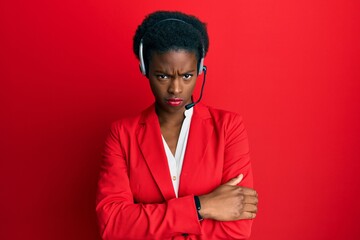 Young african american girl wearing call center agent headset skeptic and nervous, disapproving expression on face with crossed arms. negative person.