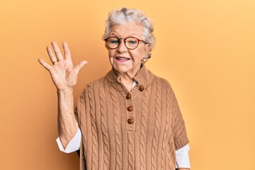 Senior grey-haired woman wearing casual clothes and glasses showing and pointing up with fingers number five while smiling confident and happy.