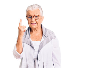 Senior beautiful woman with blue eyes and grey hair wearing casual clothes and glasses showing and pointing up with finger number one while smiling confident and happy.