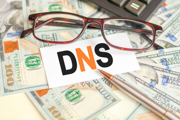 The letters DNS are written on a white card lying on the bills, glasses, pen and calculator in the background. The concept of business and Finance