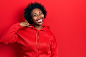 Young african american woman wearing casual sweatshirt smiling doing phone gesture with hand and fingers like talking on the telephone. communicating concepts.