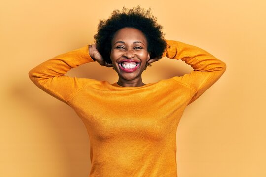 Young african american woman wearing casual clothes relaxing and stretching, arms and hands behind head and neck smiling happy