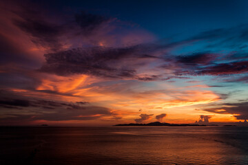 Bright sunset on sea. Orange sky, clouds over island. Thailand. 