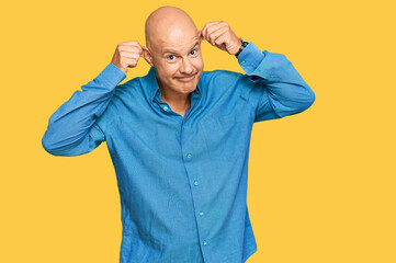 Middle age bald man wearing casual clothes smiling pulling ears with fingers, funny gesture....
