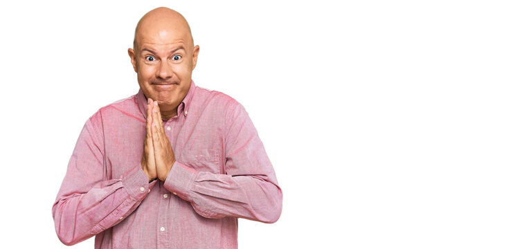 Middle age bald man wearing casual clothes praying with hands together asking for forgiveness smiling confident.