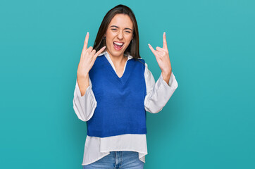 Young hispanic girl wearing casual clothes shouting with crazy expression doing rock symbol with hands up. music star. heavy concept.