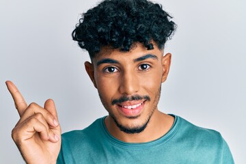 Young arab handsome man wearing casual clothes smiling happy pointing with hand and finger to the side