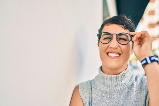 Young plus size woman smiling happy leaning on the wall at the city.