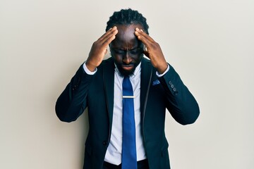 Handsome young black man wearing business suit and tie suffering from headache desperate and stressed because pain and migraine. hands on head.