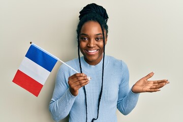 African american woman with braided hair holding france flag celebrating achievement with happy...