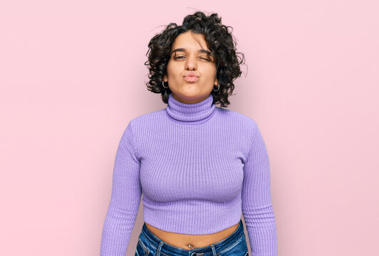Young hispanic woman with curly hair wearing casual clothes looking at the  camera blowing a kiss on air being lovely and sexy. love expression. Stock  Photo | Adobe Stock