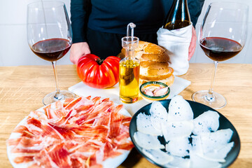 Anonymous person serving typical Catalan or Spanish food. Bread with tomato, Iberian ham, glass of...