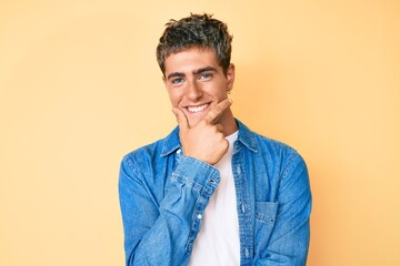 Young handsome man wearing casual clothes looking confident at the camera smiling with crossed arms and hand raised on chin. thinking positive.