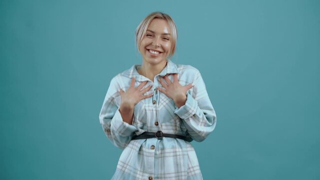 Hey, me wahh The excited young woman looks into the room pointing, then gets excited and smiles beautifully. Beautiful mature young woman, blonde, in her shirt, blue. Isolated on blue background