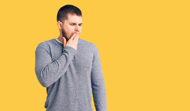 Young handsome man wearing casual sweater bored yawning tired covering mouth with hand. restless and sleepiness.