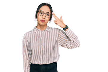 Young hispanic girl wearing casual clothes and glasses shooting and killing oneself pointing hand and fingers to head like gun, suicide gesture.