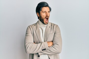 Young hispanic man with arms crossed gesture angry and mad screaming frustrated and furious, shouting with anger. rage and aggressive concept.