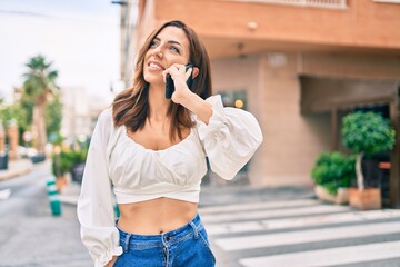 Young hispanic woman smiling happy talking on the smartphone at the city.