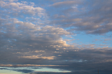 Naklejka na ściany i meble White and grey cotton-textured clouds spread across a blue sky to the horizon