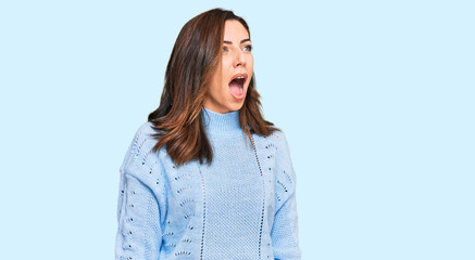 Fototapeta premium Young brunette woman wearing casual winter sweater angry and mad screaming frustrated and furious, shouting with anger. rage and aggressive concept.