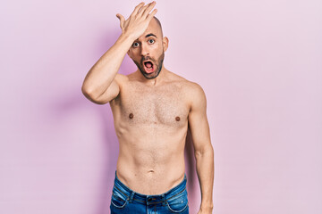 Fototapeta premium Young bald man standing shirtless surprised with hand on head for mistake, remember error. forgot, bad memory concept.