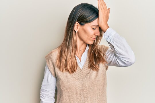 Brunette young woman wearing casual clothes surprised with hand on head for mistake, remember error. forgot, bad memory concept.