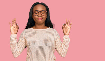 Young black woman wearing casual clothes and glasses relax and smiling with eyes closed doing meditation gesture with fingers. yoga concept.