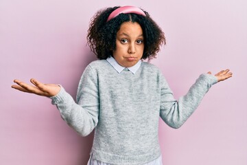 Young little girl with afro hair wearing casual clothes clueless and confused expression with arms...