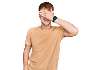 Young caucasian man wearing casual clothes smiling and laughing with hand on face covering eyes for surprise. blind concept.