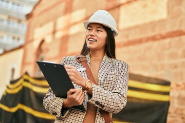 Young asian architect woman smiling happy writing on clipboard at the city.