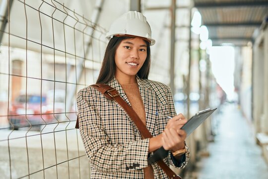 Young asian architect woman smiling happy writing on clipboard at the city.