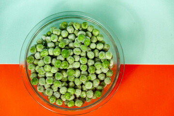 bowl with frozen peas on orange and light blue background