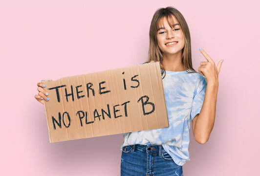 Teenager caucasian girl holding there is no planet b banner pointing finger to one self smiling happy and proud