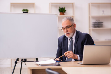 Old male employer in front of white board