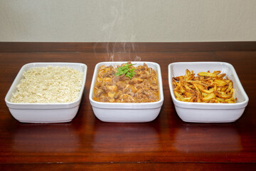 Stroganoff, ready and served with rice and chips on the table and with smoke in the stroganoff