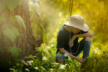 boy scout with hat, observing in great detail, plants and insects of nature. Boy in idyllic...