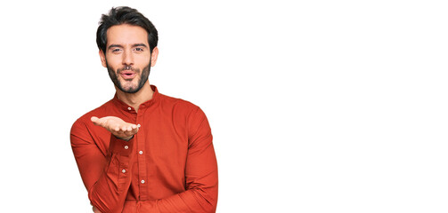 Young hispanic man wearing casual clothes looking at the camera blowing a kiss with hand on air being lovely and sexy. love expression.