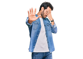 Young hispanic man wearing casual clothes covering eyes with hands and doing stop gesture with sad and fear expression. embarrassed and negative concept.