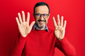 Naklejka premium Middle age hispanic man wearing casual clothes and glasses showing and pointing up with fingers number nine while smiling confident and happy.