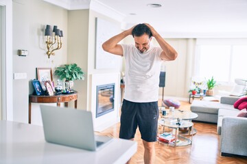 Middle age man with beard training and stretching doing exercise at home looking at sport video on computer