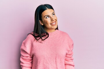Fototapeta premium Beautiful brunette woman wearing casual winter sweater looking away to side with smile on face, natural expression. laughing confident.
