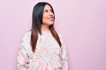 Fototapeta premium Young beautiful brunette woman wearing casual dyed sweatshirt over isolated pink background looking to side, relax profile pose with natural face and confident smile.